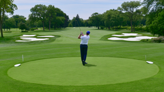A golfer mid-swing on a tee surrounded by trees