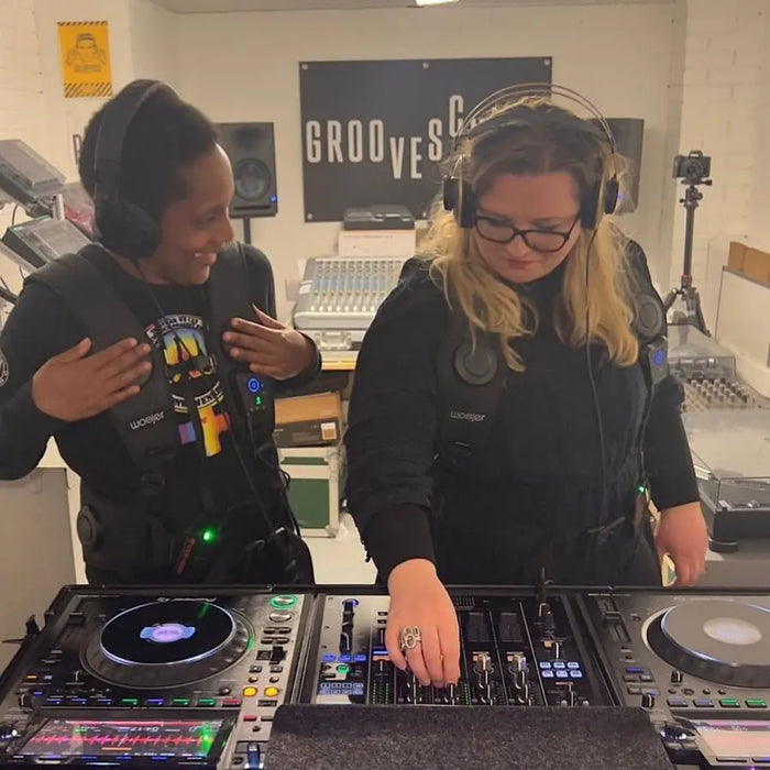 Two people wearing Woojer Vests at the DJ decks